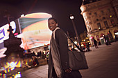 Happy young woman in city at night