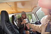 Happy young women friends enjoying coffee in camper van