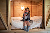 Girl playing with stuffed bunny on bed in wood loft