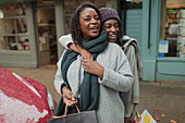 Happy mother and daughter with shopping bags on sidewalk