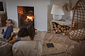 Mother and daughter cuddling by fireplace in living room