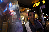 Confident young woman at urban bus stop at night