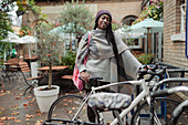 Confident young woman with bicycle on cafe patio