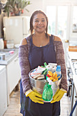 Confident woman with bucket of cleaning supplies
