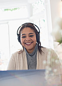 Smiling woman with headphones working from home at laptop