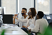 Business people in face masks working at computer in office