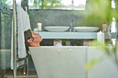Woman enjoying bubble bath in modern luxury bathroom