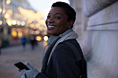 Happy young woman with smartphone on city sidewalk