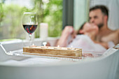 Romantic couple enjoying bubble bath and wine in soaking tub