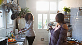 Mother and daughter doing dishes and enjoying tea in kitchen