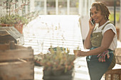 Female garden shop owner talking on smartphone in greenhouse