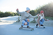 Young women friends skateboarding on beach boardwalk