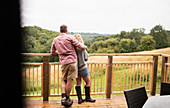 Couple hugging on cabin balcony overlooking trees
