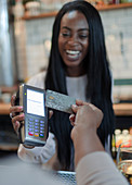 Customer paying happy female bartender with smartphone