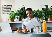 Businesswoman reviewing paperwork at breakfast in lounge