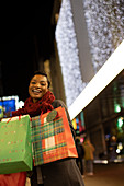 Happy young woman with Christmas shopping bags in city