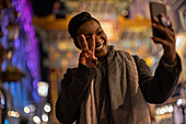 Happy young woman taking selfie gesturing peace sign