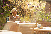 Woman with coffee at sunny garden cafe table