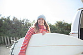 Happy young female surfer holding surfboard
