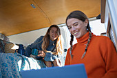 Happy young women friends using laptop in camper van