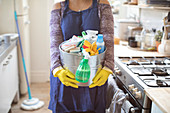 Woman holding bucket of cleaning supplies in kitchen
