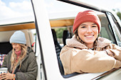 Happy young woman on road trip at van window