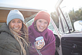 Happy young women friends with coffee in camper doorway