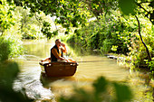 Man talking on smartphone and fly fishing in boat on river
