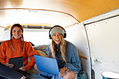 Happy young women friends using technology in camper van