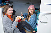 Happy young women friends waiting instant noodles in van