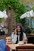 Woman talking on smartphone and eating lunch on cafe patio