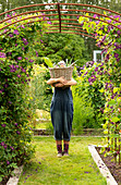 Woman holding large basket of harvested garden vegetables
