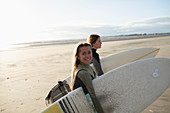 Happy young female surfers with surfboards on sunny beach