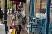 Young woman with shopping bag talking on smartphone