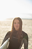 Young female surfer with wet hair on sunny beach