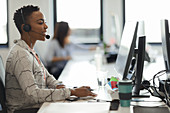 Woman with headset working at computer in call centre office