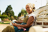 Happy female garden shop owner taking coffee break on bench