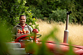 Happy man with fresh harvested apples at tractor in orchard