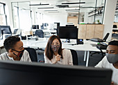 Business people in face masks working at computer in office