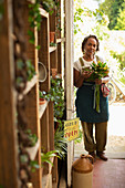 Confident female florist with flower bouquet in shop doorway
