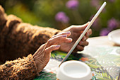 Woman using digital tablet at patio table
