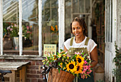 Female florist with flowers in bike basket outside shop