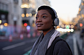 Beautiful young woman in headphones on city street
