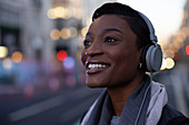 Happy young woman in headphones on city street