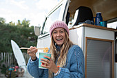 Happy young woman eating instant noodles at camper van