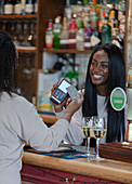 Customer paying bartender with smart card at pub counter