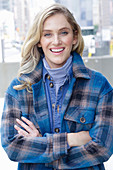 A young blonde woman wearing blue denim dungarees and a checked jacket