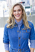 A young blonde woman wearing blue denim dungarees