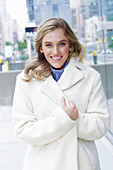 Junge blonde Frau in weißem Mantel