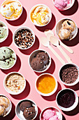 Verschiedene Eissorten in Pappbechern mit verschiedenen Toppings
